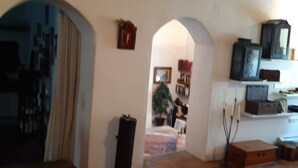 A living room with wooden flooring, a patterned rug, and a television on a stand. There are two archways leading to another room. - Country Residence Turicchi (Dicomano)