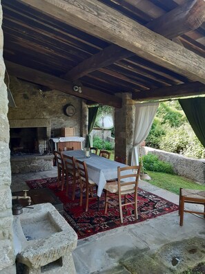 An outdoor dining area with a stone table and chairs, a rustic stone wall, and a view of greenery. - Country Residence Turicchi (Dicomano)