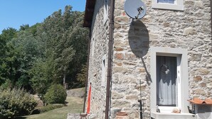 A stone building with a satellite dish, a small window, and a door with a curtain. - Country Residence Turicchi (Dicomano)