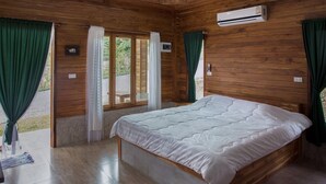Habitación con paneles de madera, una cama, un equipo de aire acondicionado y vistas a través de un vidrio.