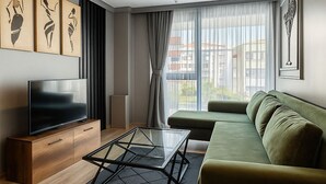 A modern living room with a flat-screen TV, a glass coffee table, a green sofa, and artwork on the walls. - On4 Rooms & Suites (Istanbul)