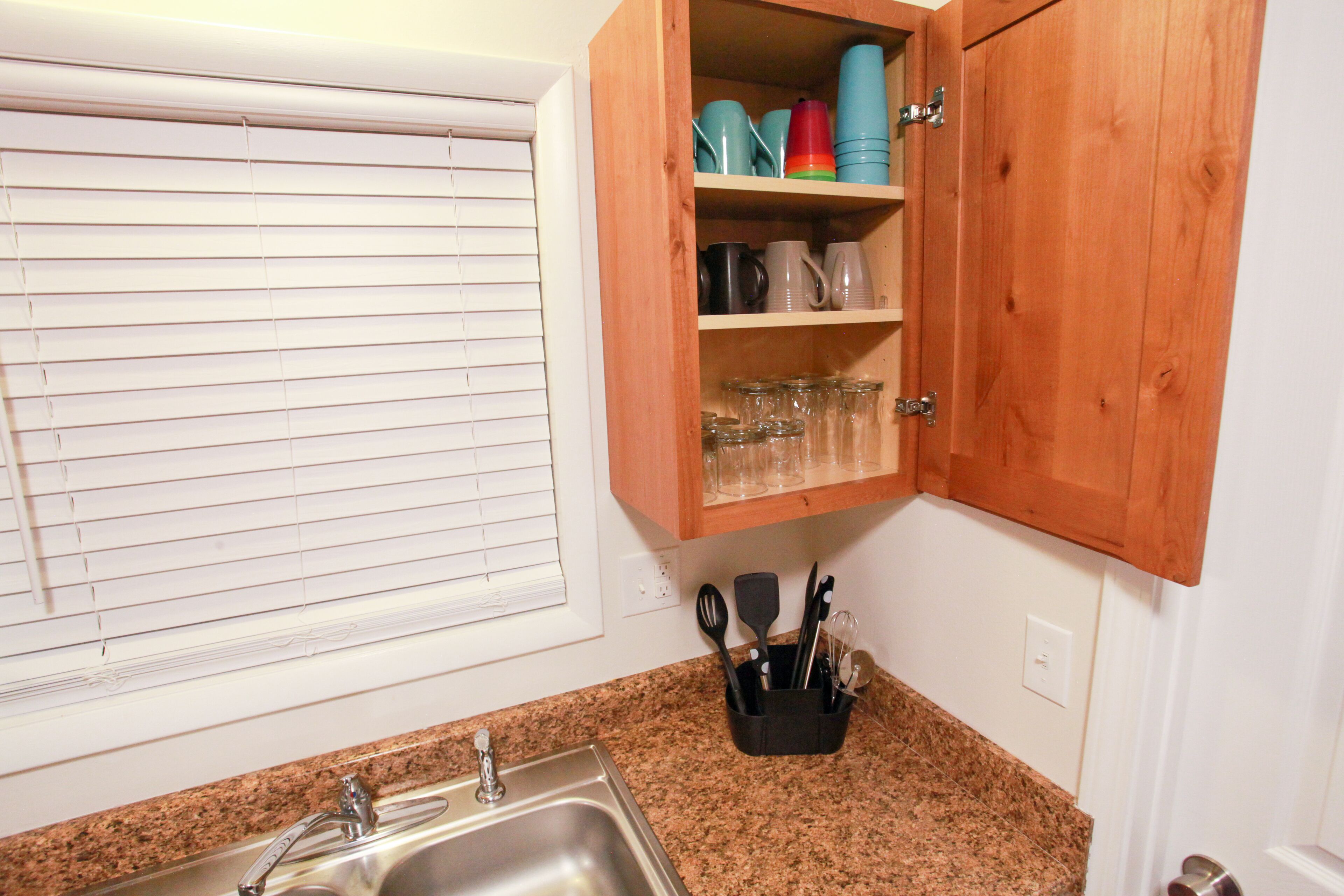 Una cocina con encimera de granito, pileta de acero inoxidable y muebles de madera.