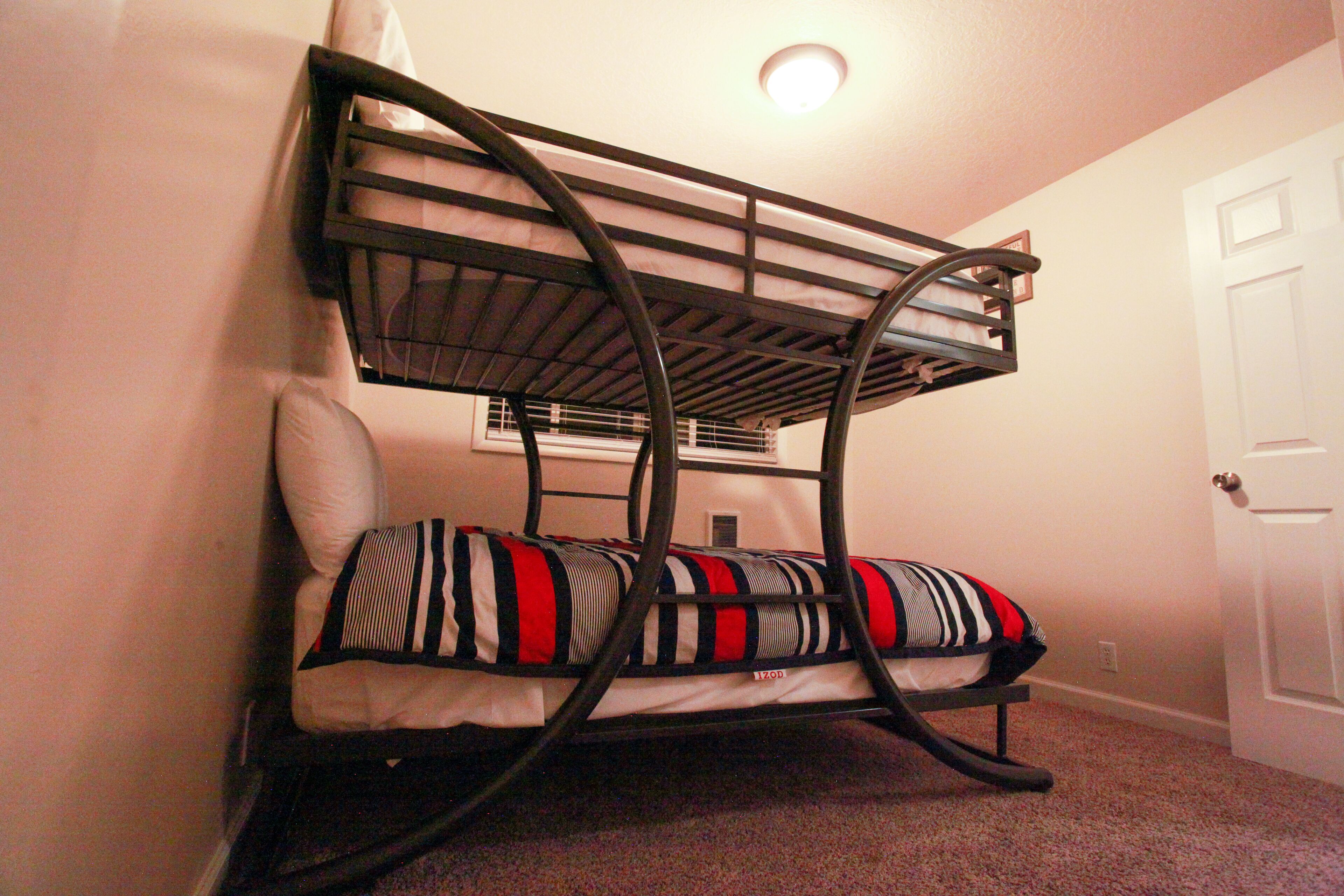A bunk bed with a headboard and footboard, a pillow, and a wall-mounted shelf.