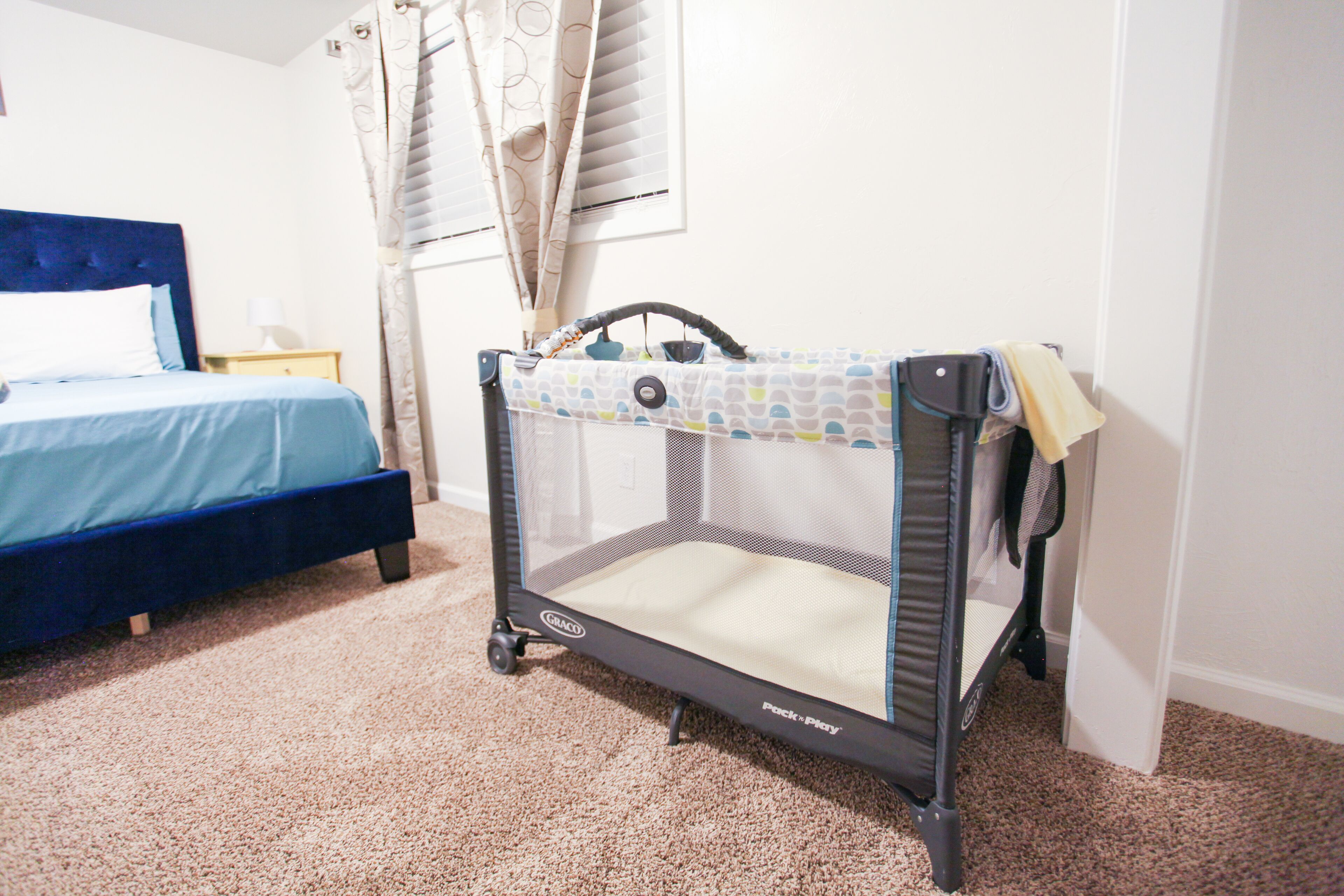 A room with a bed, a crib, and a carpeted floor.