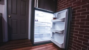 A refrigerator with a freezer compartment, a door, and a brick wall. - Kingston East (Rexburg)
