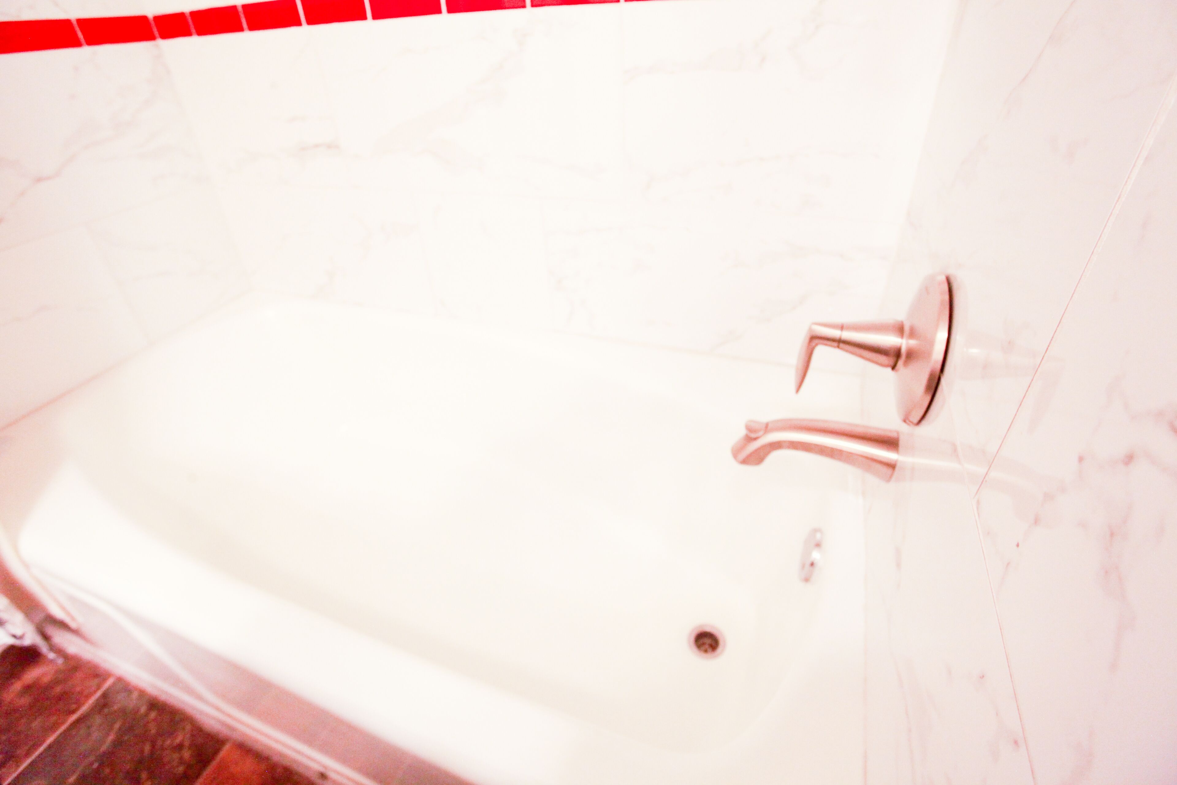 Una bañera blanca con un grifo moderno, frente a una pared de mármol blanco.