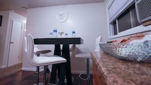 A dining area with a table and chairs, a wall-mounted sign, and a window with an air conditioning unit. - Kingston East (Rexburg)
