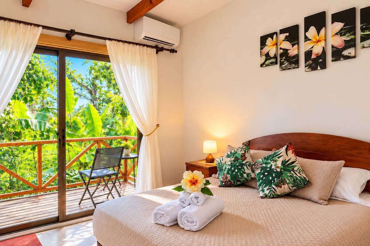Une chambre d’hôtel avec un lit, une table de chevet, une lampe, une chaise et une vue sur la verdure.