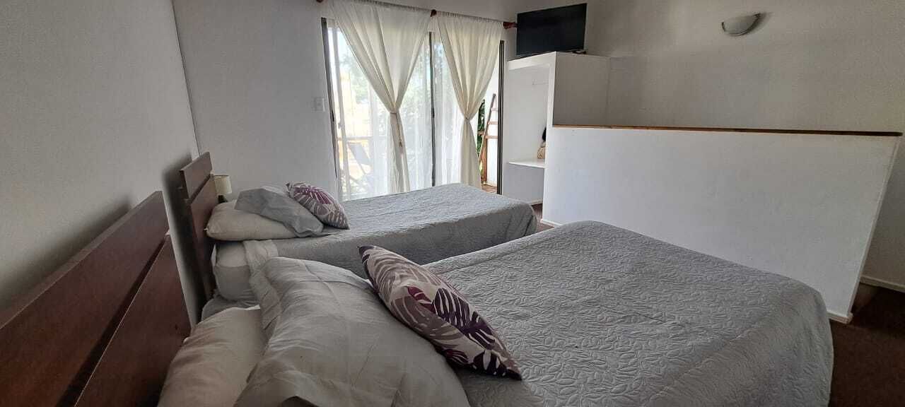 Ett hotellrum med två sängar, en tv som är monterad på väggen och ett fönster med gardiner.