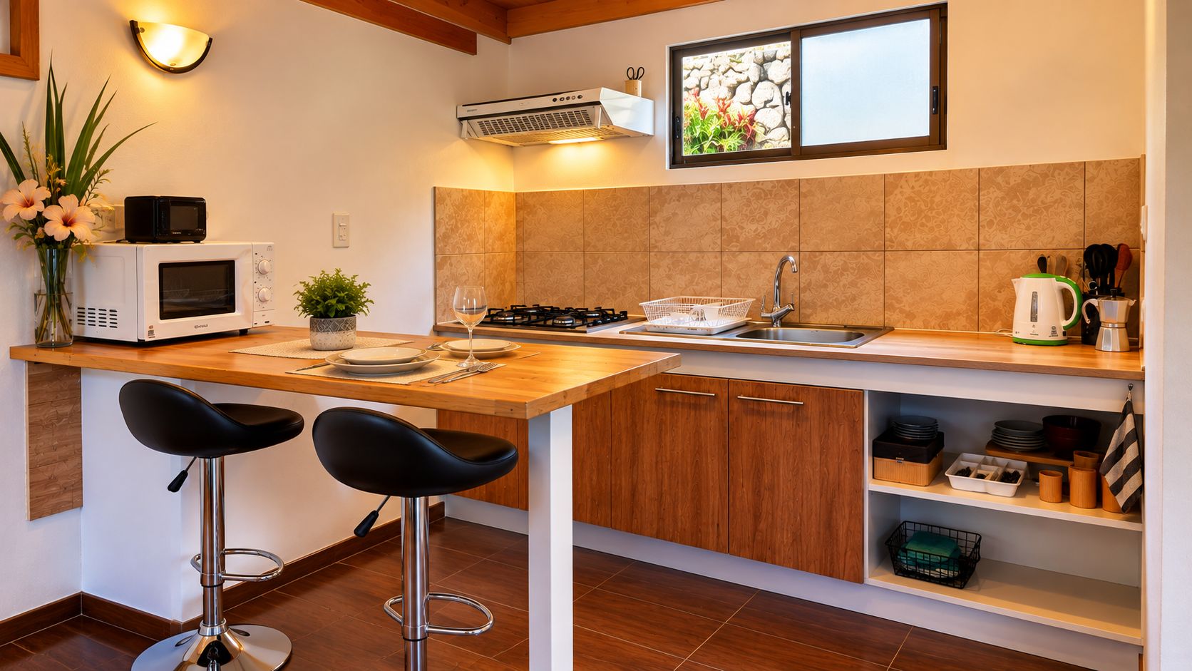 Une cuisine moderne avec un plan de travail en bois, deux tabourets de bar noirs, un four à micro-ondes, une cuisinière à gaz, un évier et divers ustensiles de cuisine.
