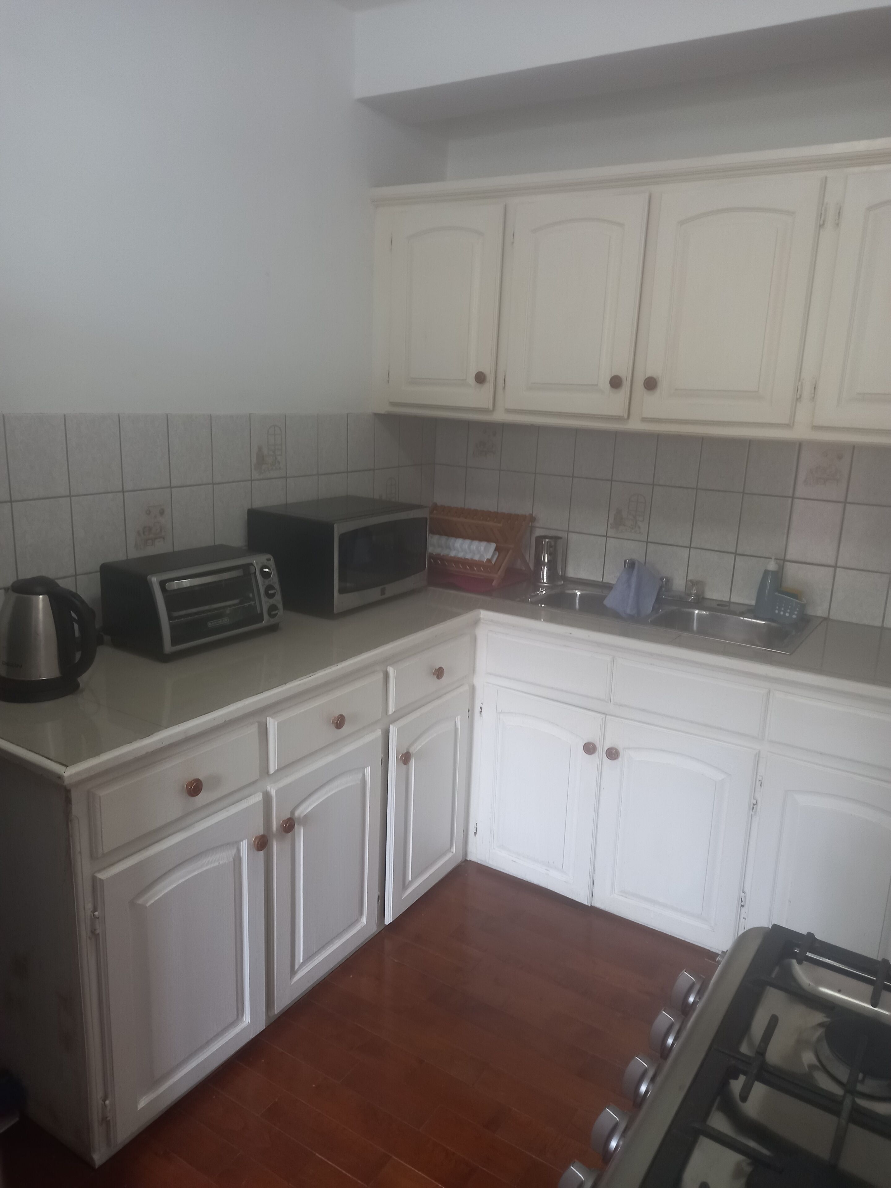 A kitchen with white cabinets, a microwave, a toaster, and a gas stove.