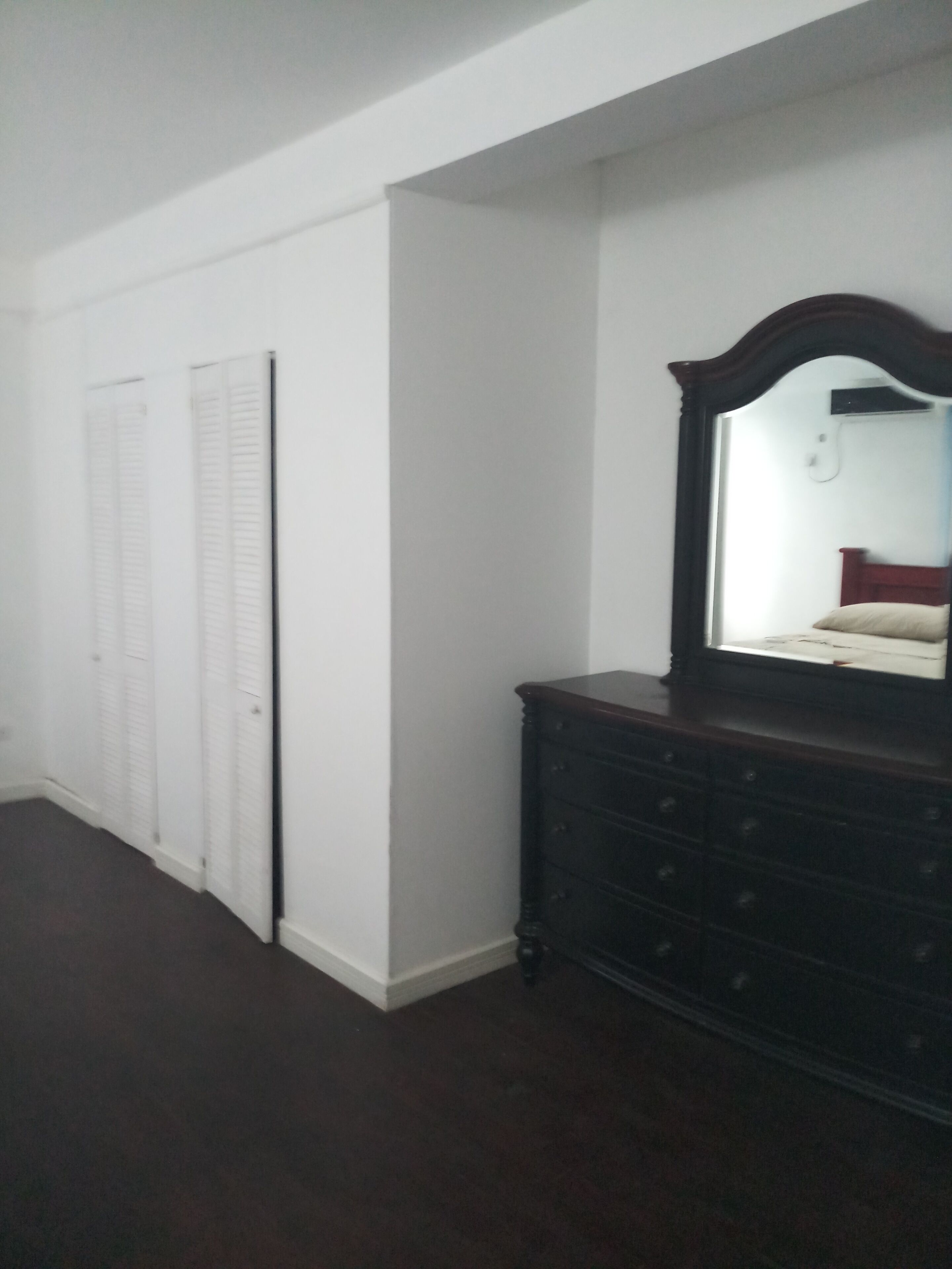 A bedroom with a dresser, a mirror, and a closet.