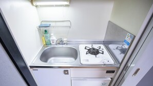 Uma cozinha compacta equipada com pia, fogão e um pequeno frigorífico.