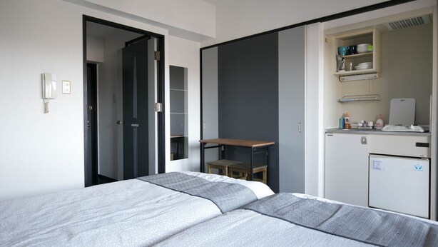 Quarto de hotel moderno com cama, escrivaninha e mini-geladeira.