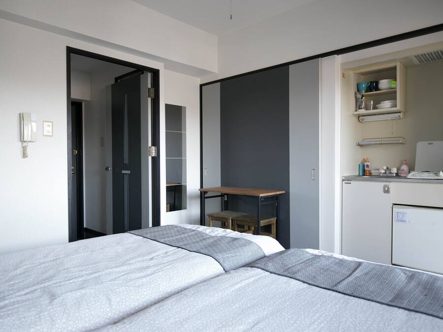 Quarto de hotel moderno com cama, escrivaninha e mini-geladeira.