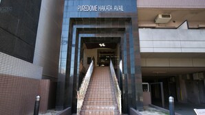 Entrada de um edifício com uma placa indicando "PUREDOME HAKATA AVAIL".