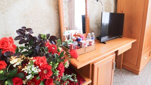 Una cómoda de madera con espejo, un televisor y un arreglo floral.