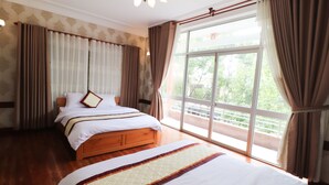 Un dormitorio amplio con una cama grande, un cabecero de madera y vistas a la vegetación a través de un ventanal.