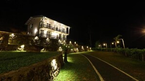 Un edificio a due piani con un balcone al piano superiore, circondato da mura in pietra e illuminato da lampioni.