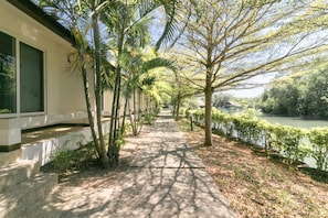 A pathway lined with trees and a body of water on one side. - Chaiyo Resort (Wichit)