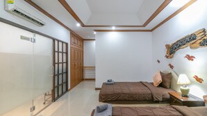 Une chambre d’hôtel avec deux lits, une armoire en bois, une porte en verre et un climatiseur fixé au mur.