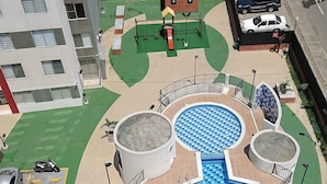 A rooftop pool with a checkered pattern, surrounded by a circular deck and a small play area. - Apartamento Prados Del Norte (Cali)