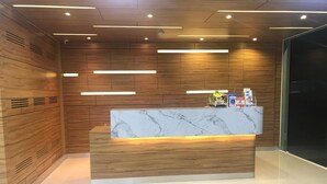 A reception desk with a marble top, wooden paneling on the walls, and recessed lighting. - Thawan Apartment (Satun)