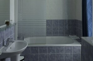 A bathroom with a bathtub, a sink, and a mirror. - Hôtel de Paris La Défense (Puteaux)