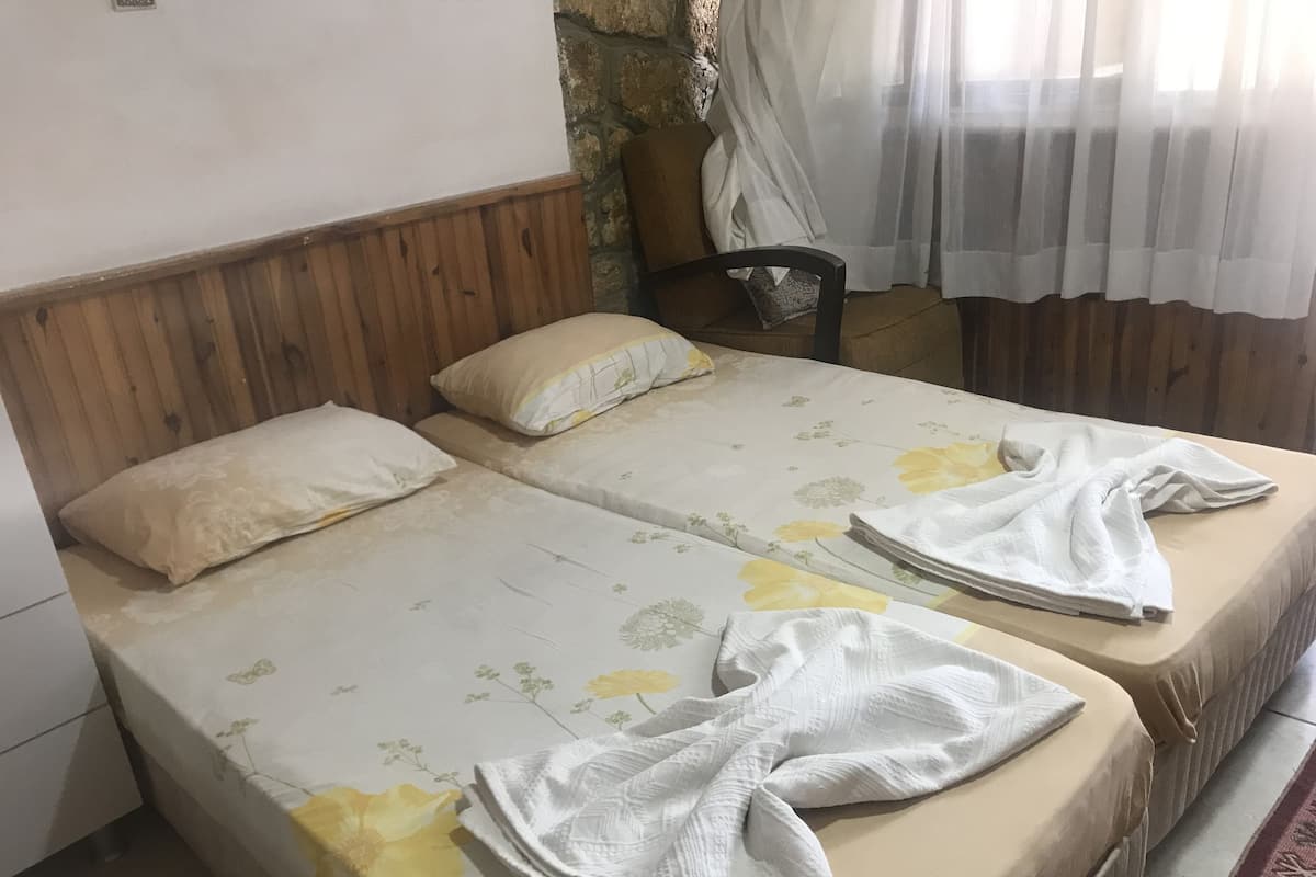 A double bed with floral bedding, a wooden headboard, and a small bedside table.