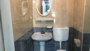 A bathroom with a pedestal sink, a toilet, and a mirror above the sink. - Kur-tur Otel (Denizli)