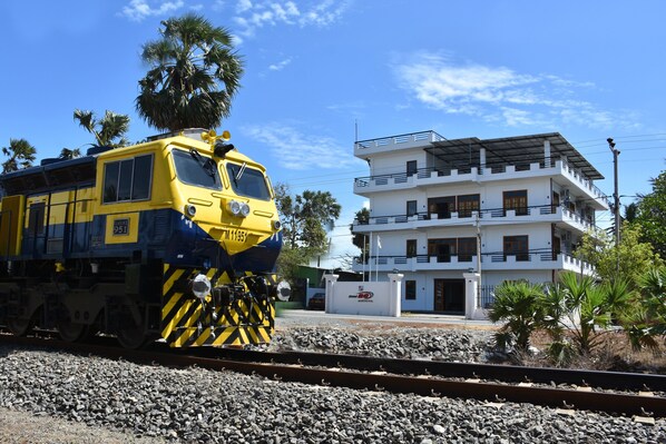 A yellow and blue train on tracks with a white building in the background.