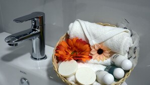Uma pia de banheiro com torneira cromada e uma cesta de vime com artigos de higiene pessoal e flores decorativas.