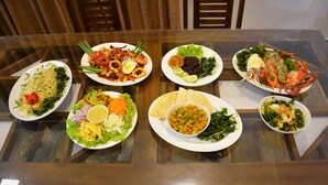 Uma mesa de vidro com diversos pratos de comida, incluindo saladas, legumes e frutos do mar.