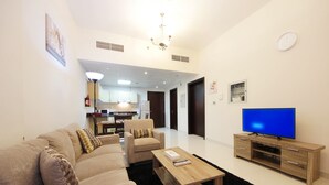 Ein modernes Wohnzimmer mit Sofa, Couchtisch, TV-Möbel und einer Küche im Hintergrund.