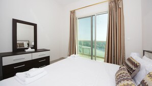 Ein Hotelzimmer mit einem großen Bett, einer Kommode mit Schubladen, einem Spiegel und einem Balkon mit Vorhängen.