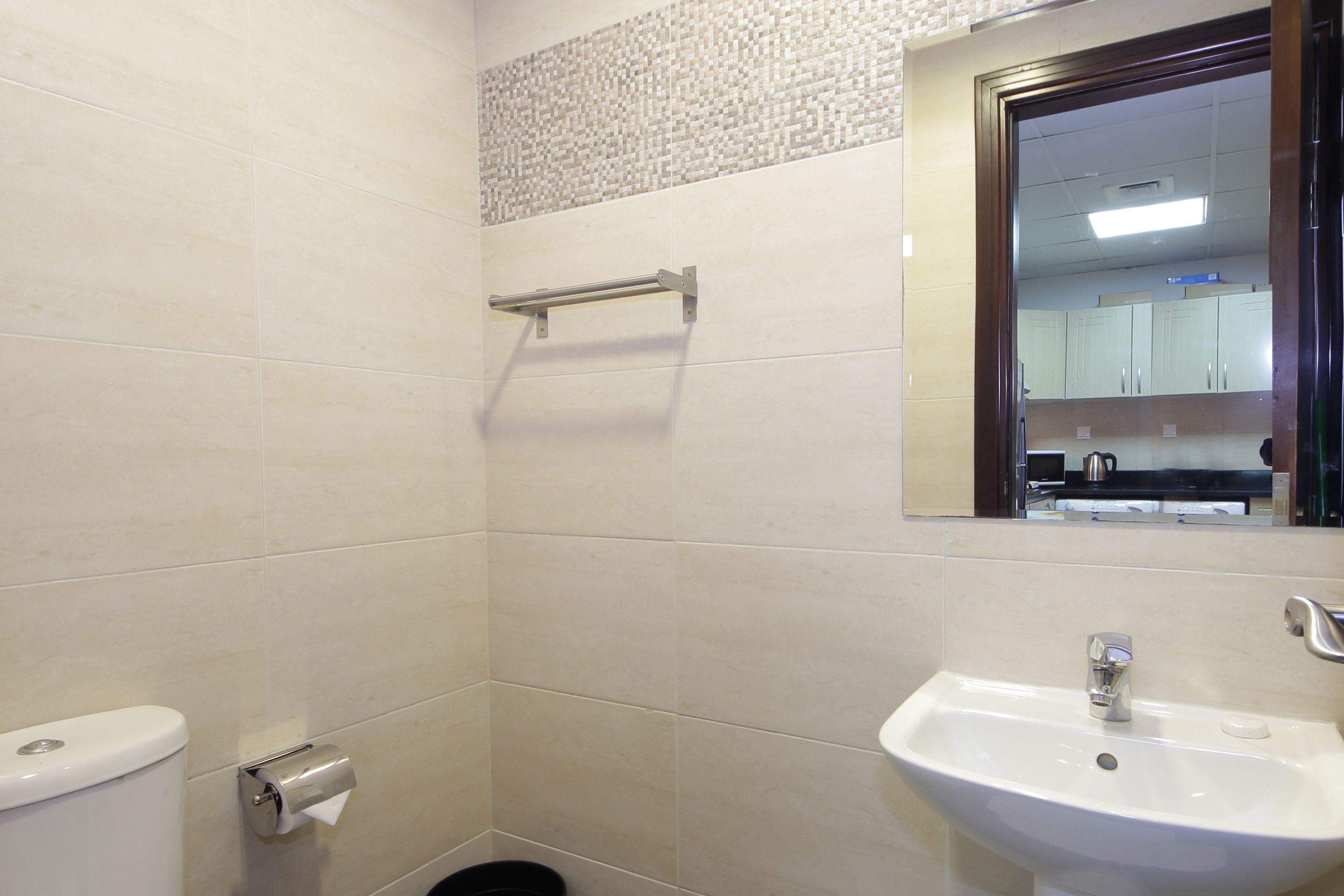 Un baño con inodoro, secamanos, lavabo y espejo.