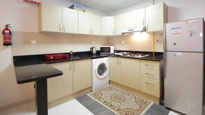 Eine kleine Küche mit Waschmaschine, Mikrowelle und Kühlschrank.
