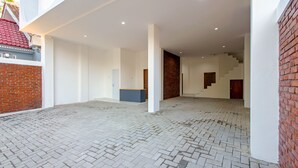 Un espacio interior amplio con piso de diseño espiga, paredes blancas y una pared de ladrillo a la derecha.