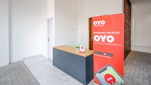 Un área de recepción con mostrador, un expositor rojo y una puerta.