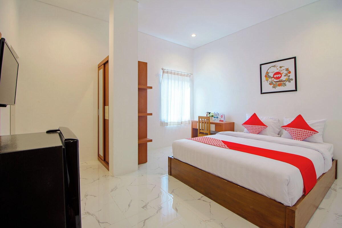 Una habitación de hotel con cama, escritorio, silla y televisor.