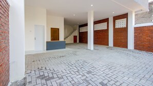 Un espacio interior con pared de ladrillo, puerta de madera, escalera y piso con diseño.