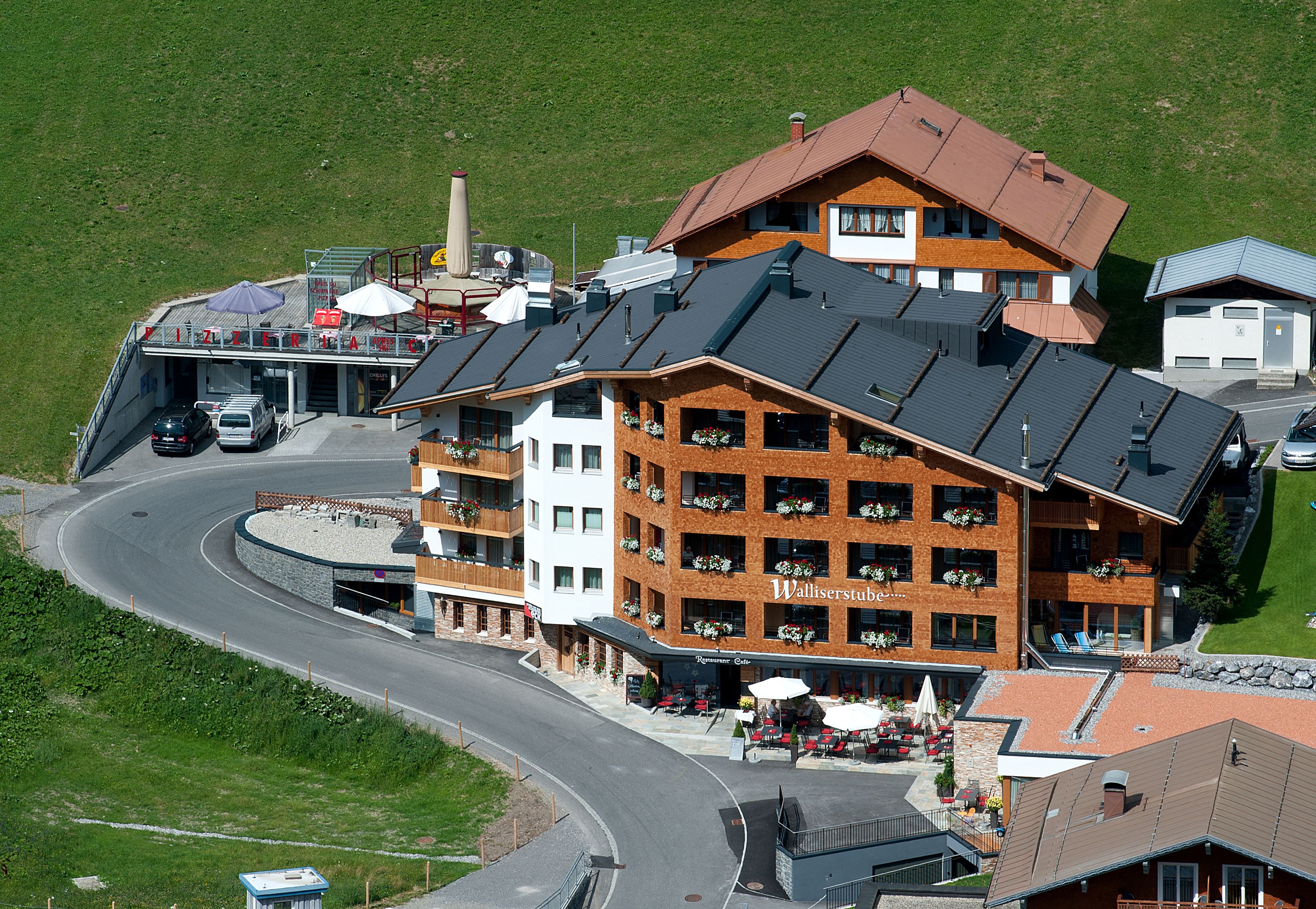 A multi-story hotel with a ski lift, a curved road, and outdoor seating.