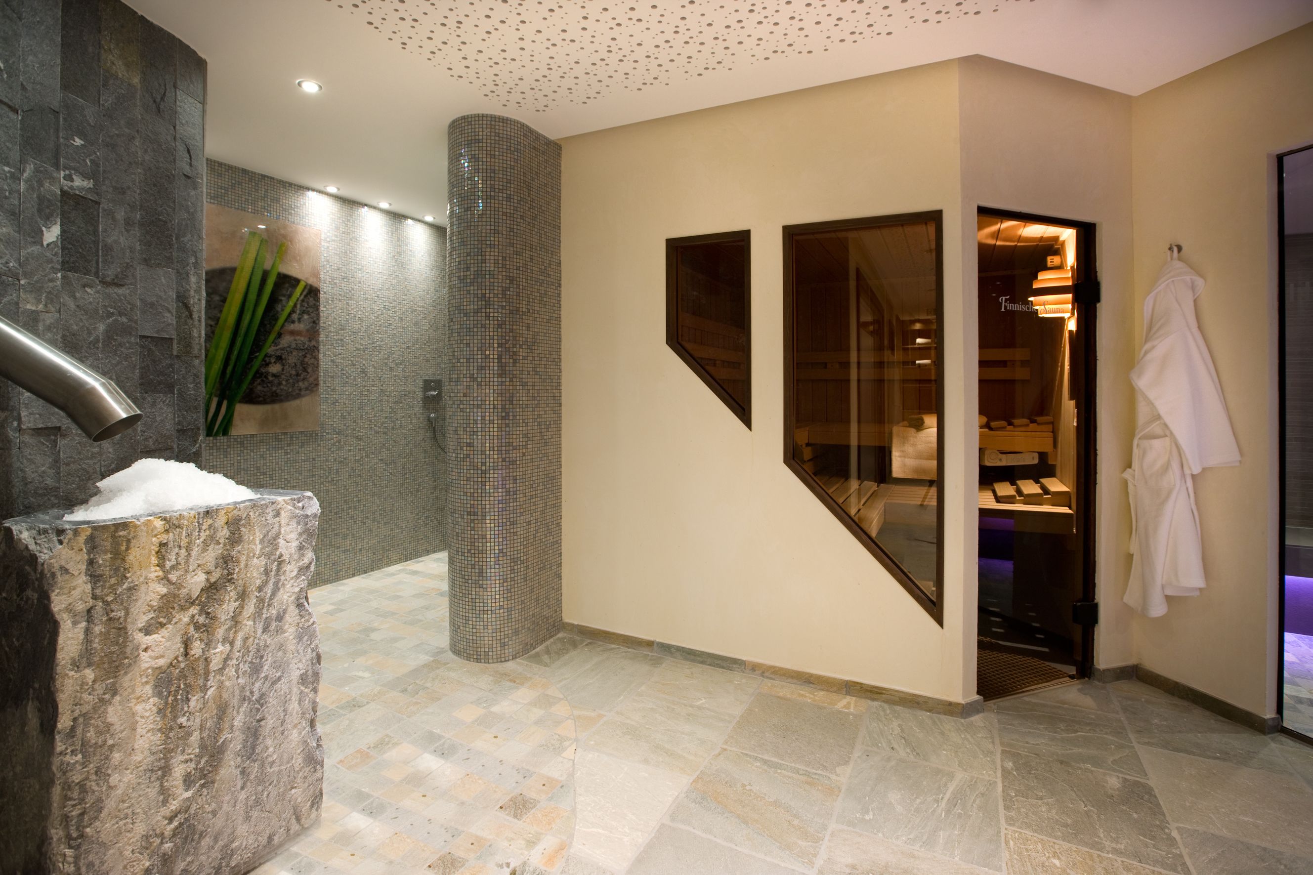 A modern bathroom with a stone sink, a glass shower enclosure, and a visible spa area.