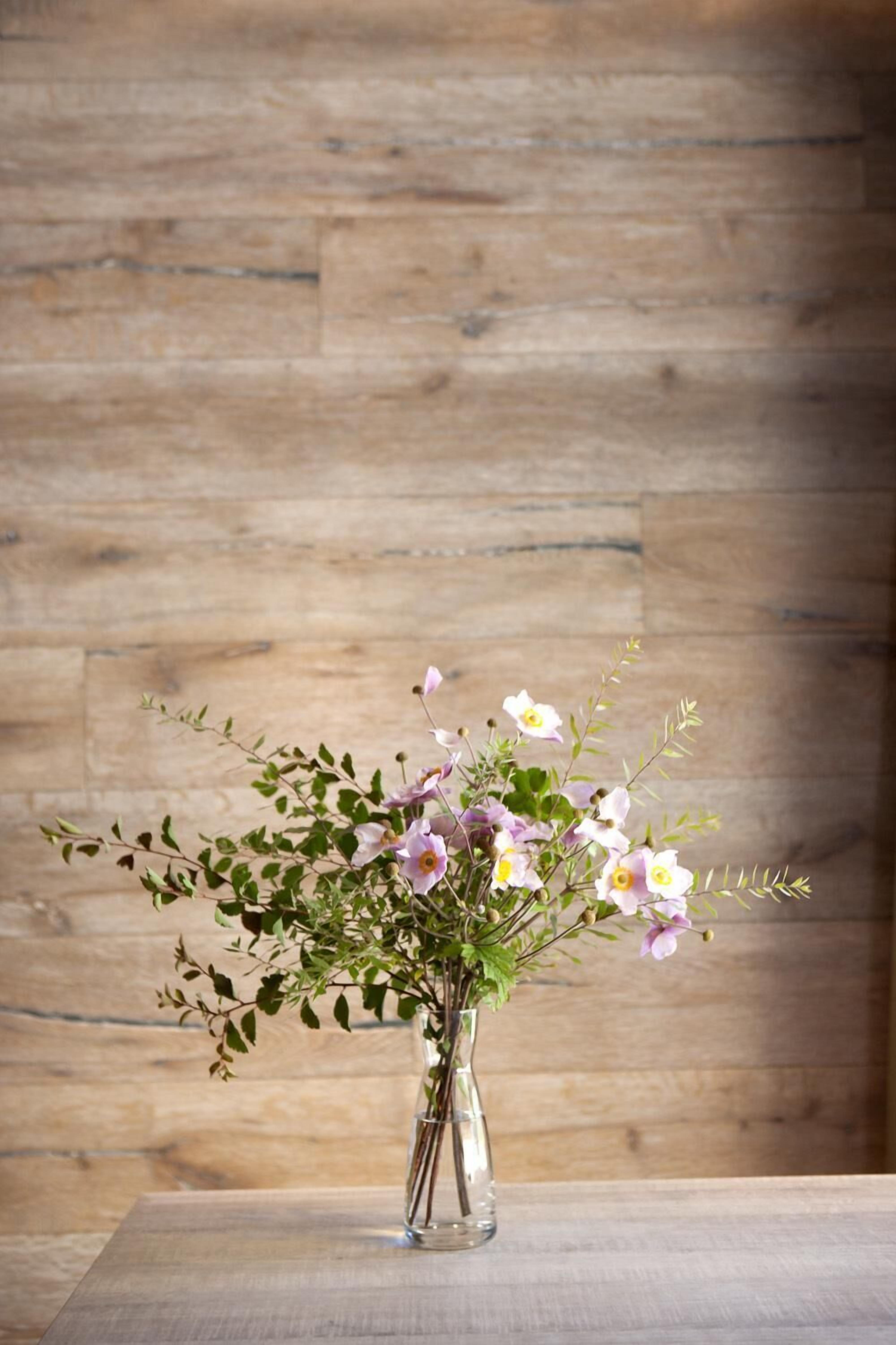 A clear view of a wooden wall and a table with a vase of flowers.