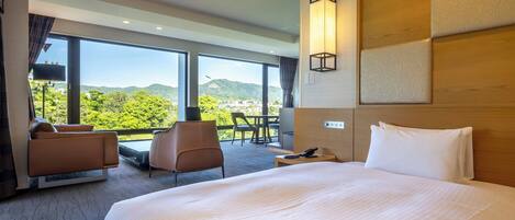 Habitación de hotel con una cama grande, un escritorio, una silla y vistas a las montañas.
