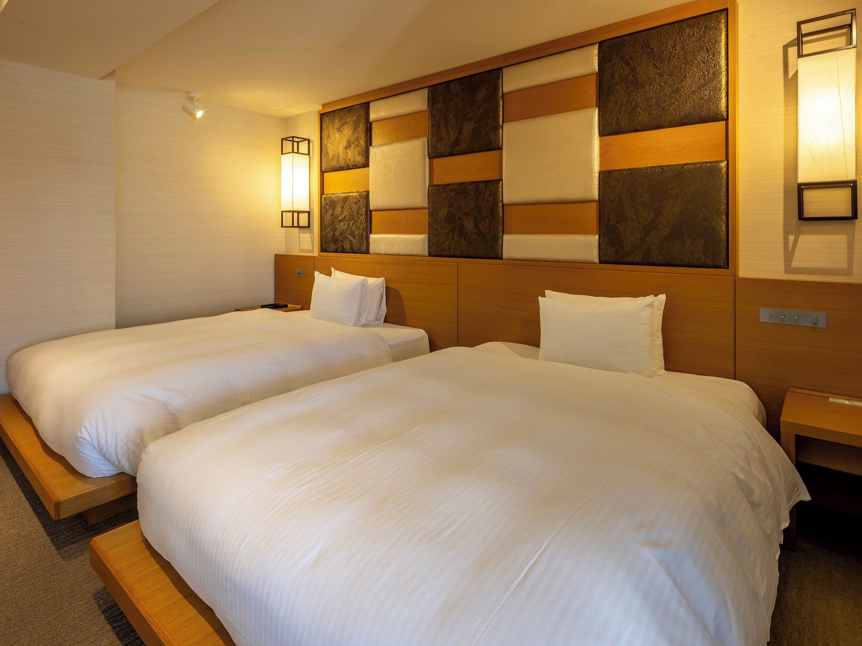 Een hotelkamer met twee bedden, houten hoofdeinden en een decoratief paneel aan de muur.