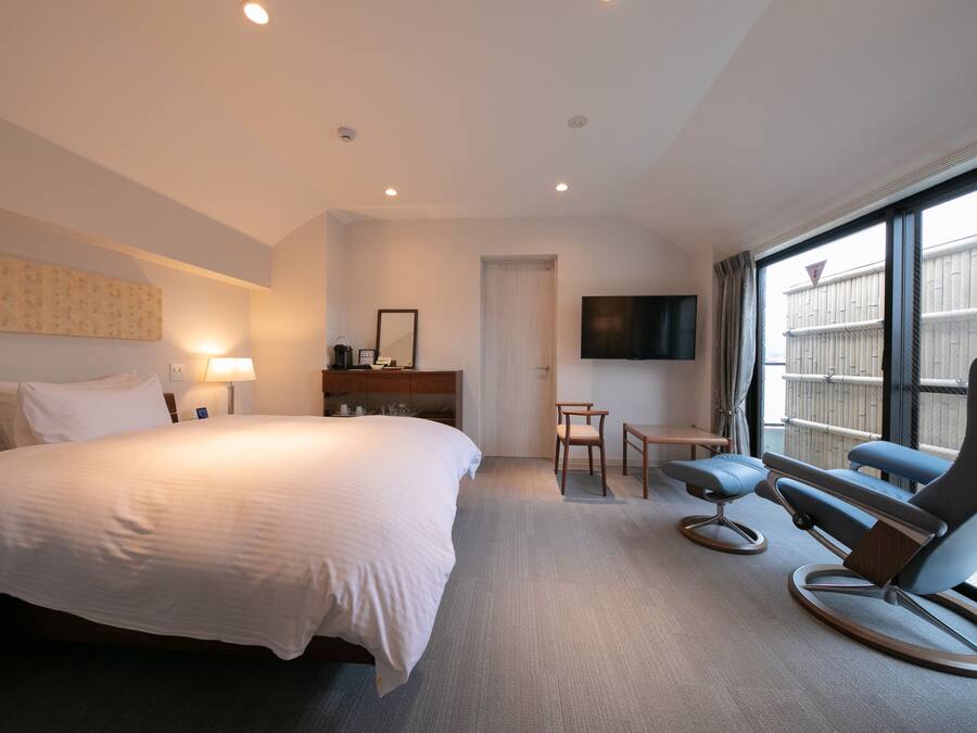 Habitación de hotel con una cama grande, un escritorio, una silla, un televisor y una ventana con vistas al exterior.