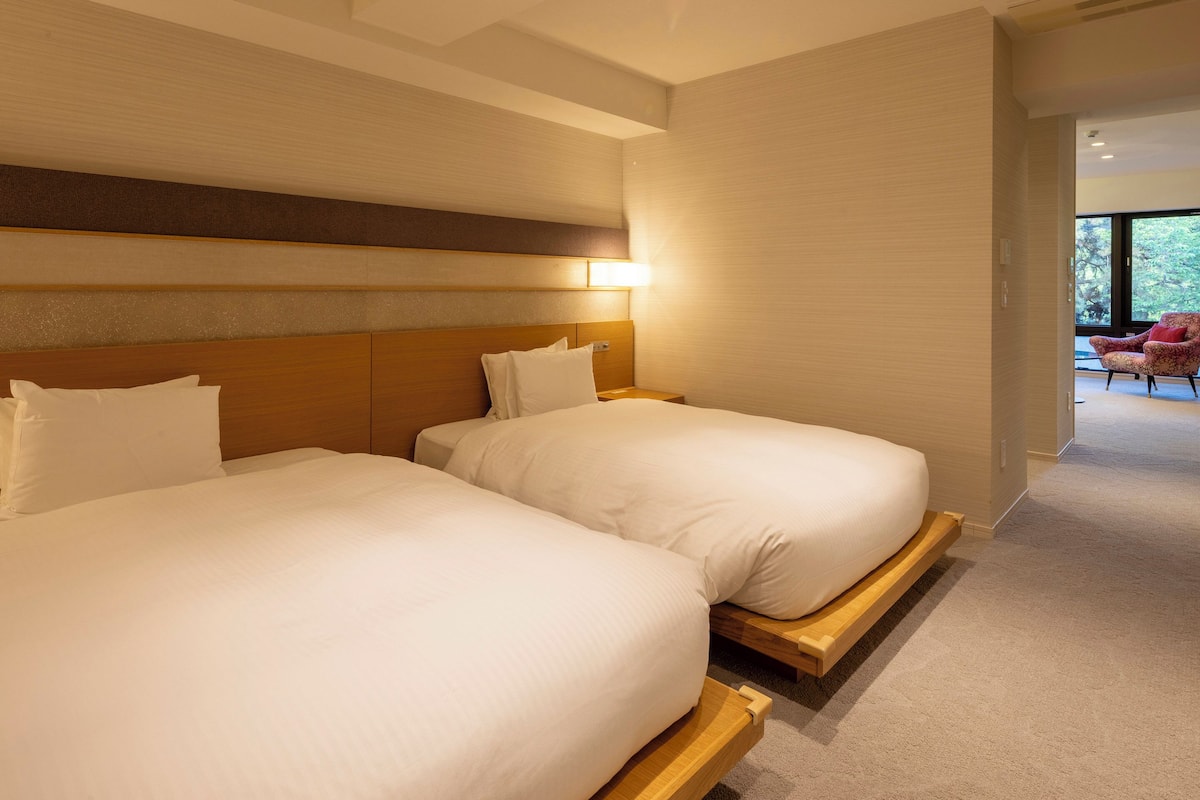 A hotel room with two beds, a wooden headboard, and a view of the outdoors.