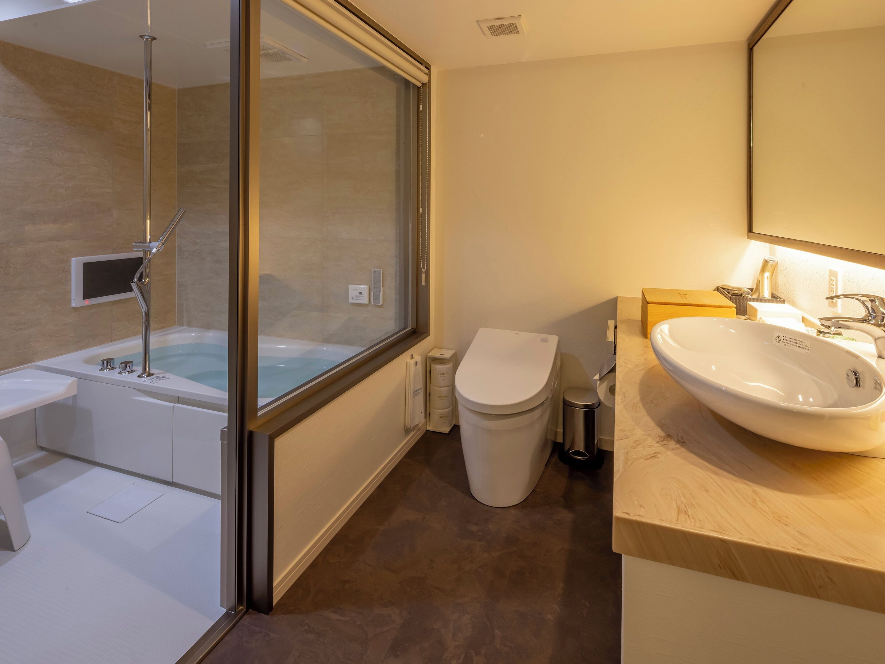 A modern bathroom with a glass-enclosed shower, a toilet, and a sink with a mirror above.