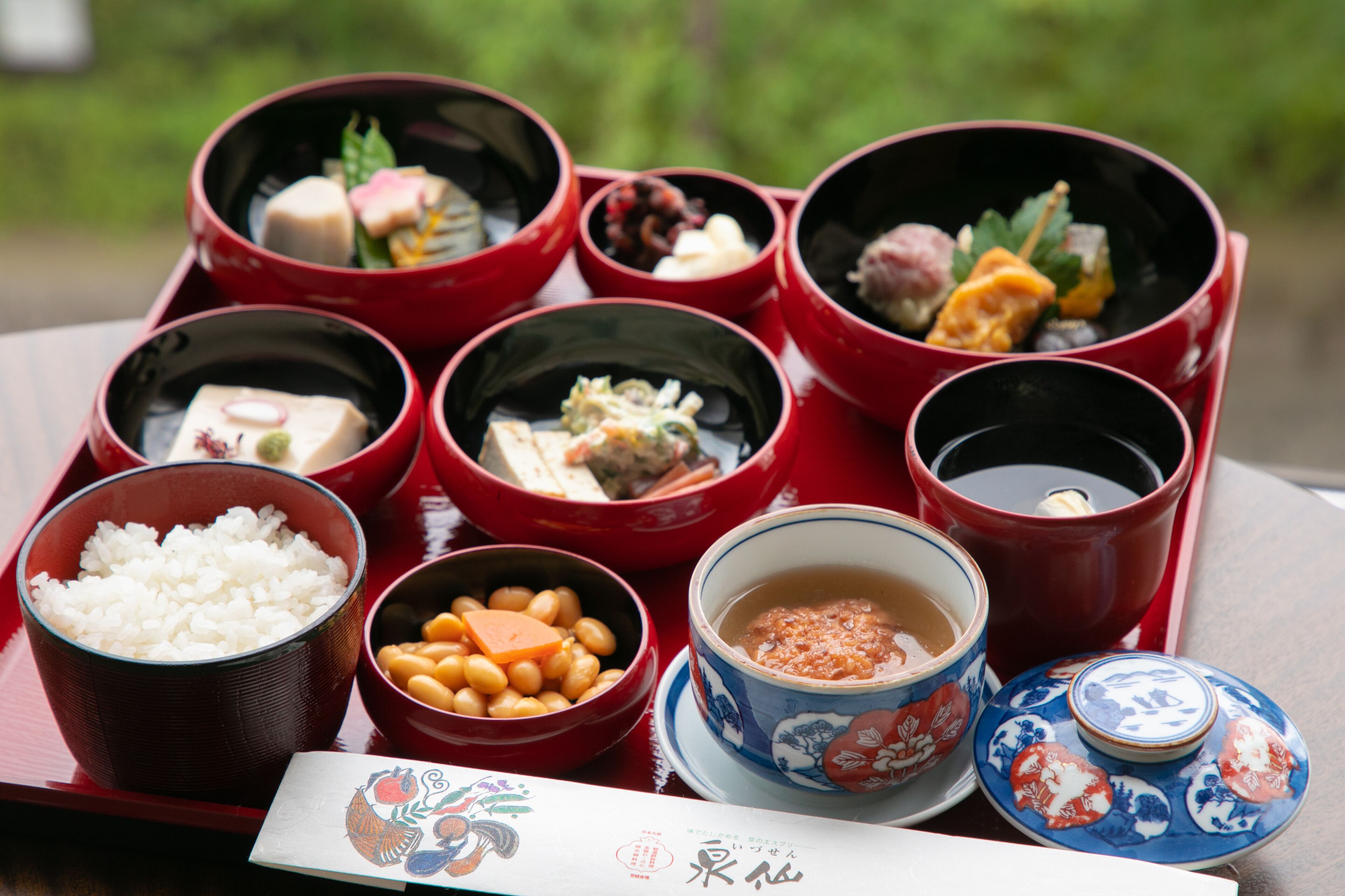 A tray with various dishes including rice, beans, and soup, accompanied by a decorative menu.
